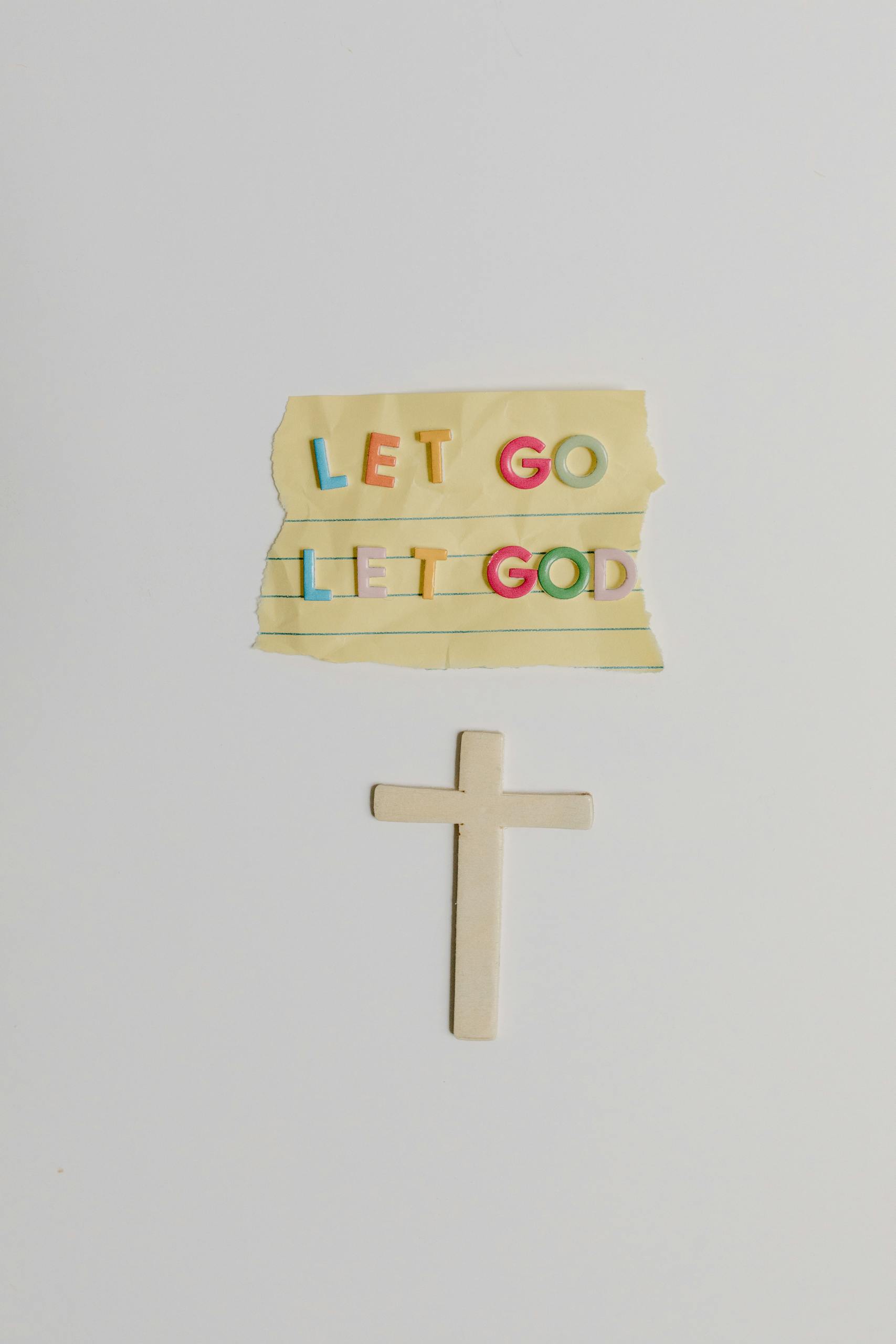 Colorful 'Let Go Let God' note and cross symbol illustrating Christian faith.